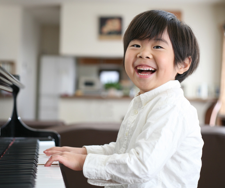 笑顔でピアノを弾く男の子の写真